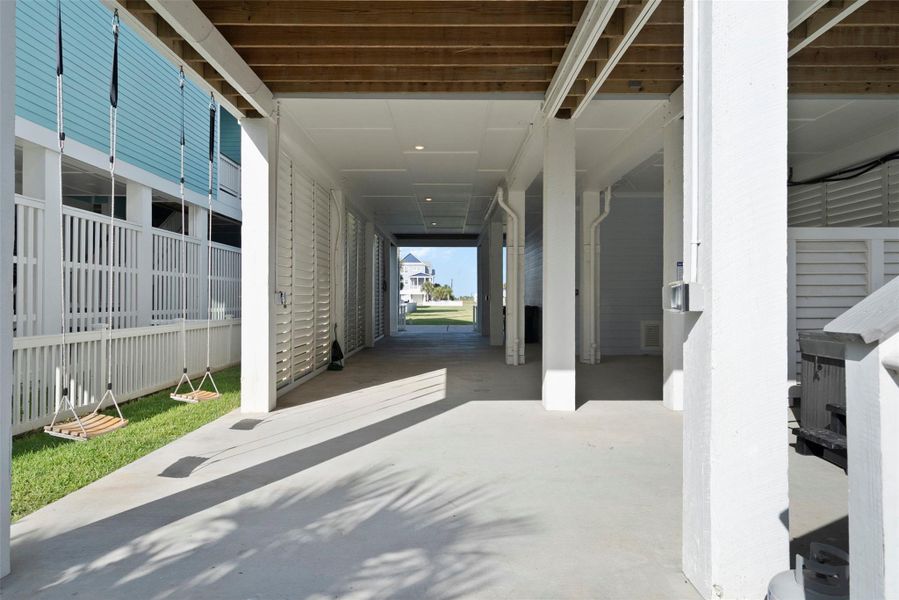 This under-house breezeway offers a serene, shaded passage from front to back, enhanced by two charming swing seats that invite relaxation and coastal daydreams. Designed for both play and pause, this open-air retreat adds character and casual elegance to the home’s modern seaside vibe. This under-house breezeway offers a serene, shaded passage from front to back, enhanced by two charming swing seats that invite relaxation and coastal daydreams. Designed for both play and pause, this open-air retreat adds character and casual elegance to the home’s modern seaside vibe.