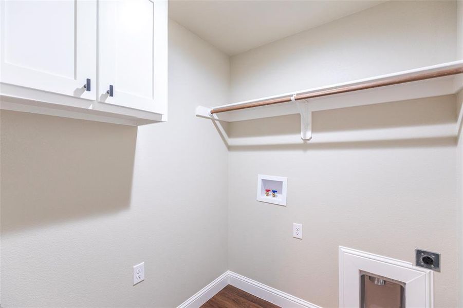 Utility area featuring white shaker-style cabinetry with matte black hardware, a wooden clothes rod, and wood-finish flooring