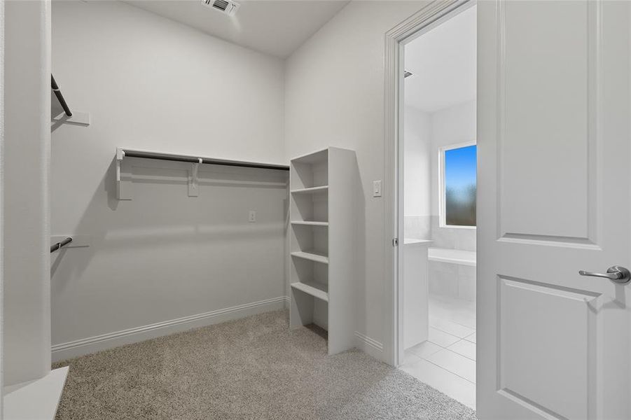 Spacious closet with light colored carpet and light tile patterned flooring