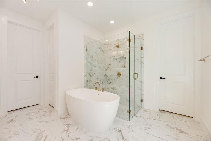 Full bathroom with a marble finish shower, a freestanding bath, light marble finish flooring, and recessed lighting Full bathroom with a marble finish shower, a freestanding bath, light marble finish flooring, and recessed lighting