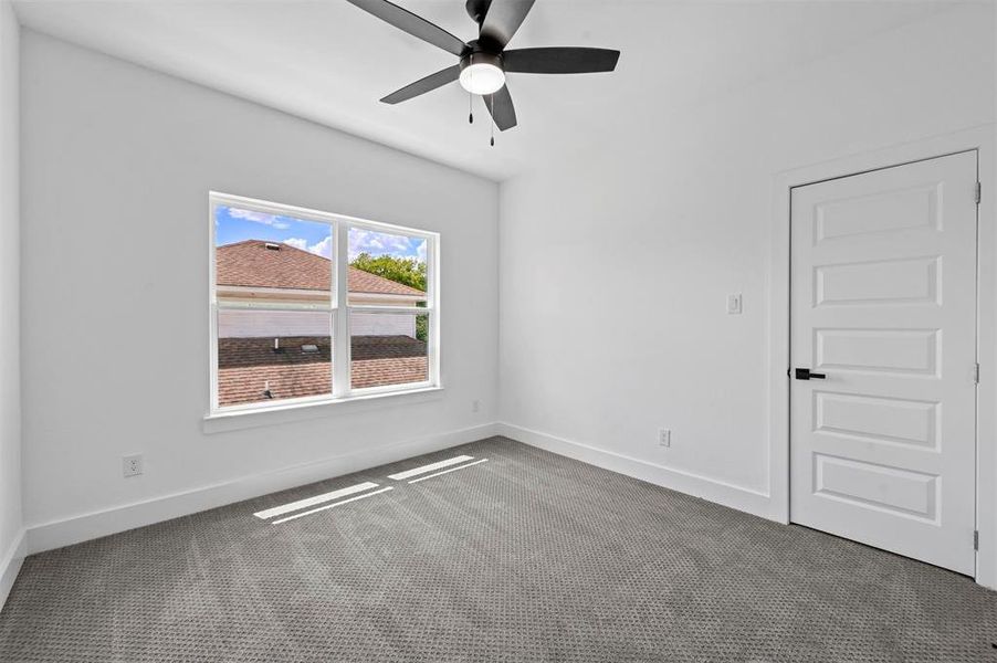 Carpeted empty room featuring ceiling fan