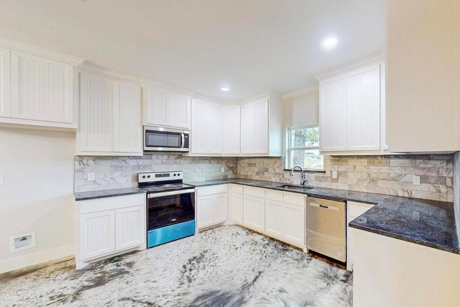 Kitchen with white cabinets, appliances with stainless steel finishes, and sink