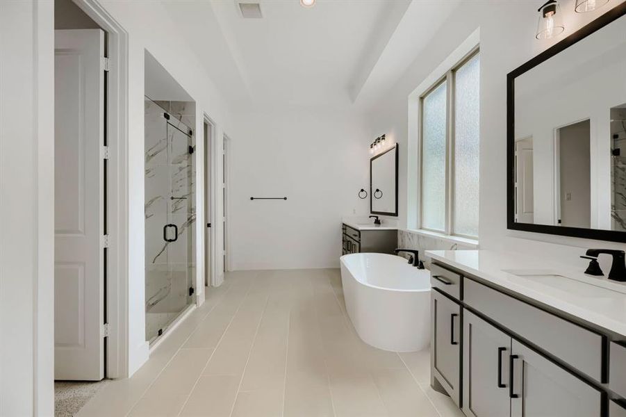 Bathroom with two vanities, a marble finish shower, and a freestanding tub