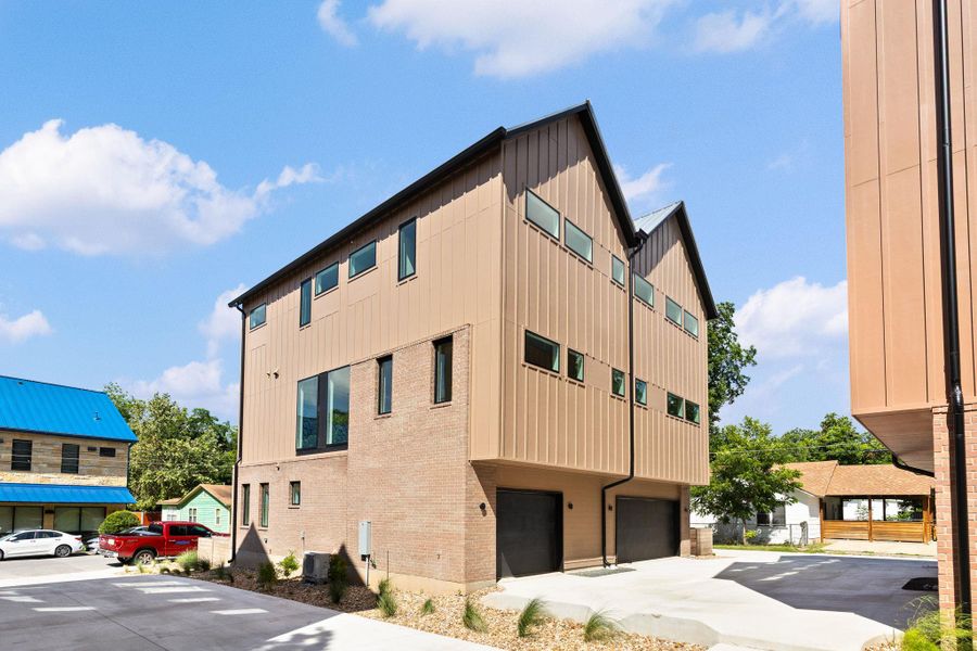 Modern townhomes feature sleek vertical siding, brick accents, and integrated garages, exuding contemporary charm.