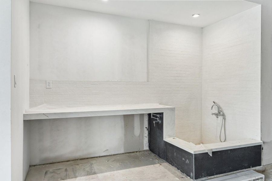 Located off of the garage is a dog washing station! There is a slab quartz counter, tile backsplash and shower surround.  Polished Chrome wall-mounted tub filler and handheld shower.  Also for convenience, is a wall mounted pot filler also finished in Chrome.