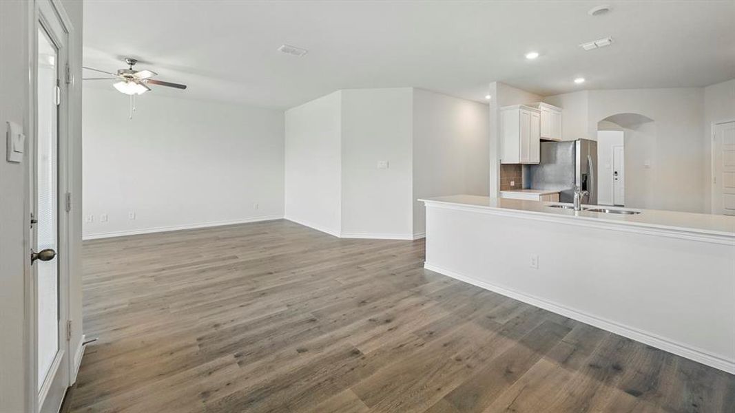 Open-concept living area featuring wood-finish flooring, white walls, and a ceiling fan