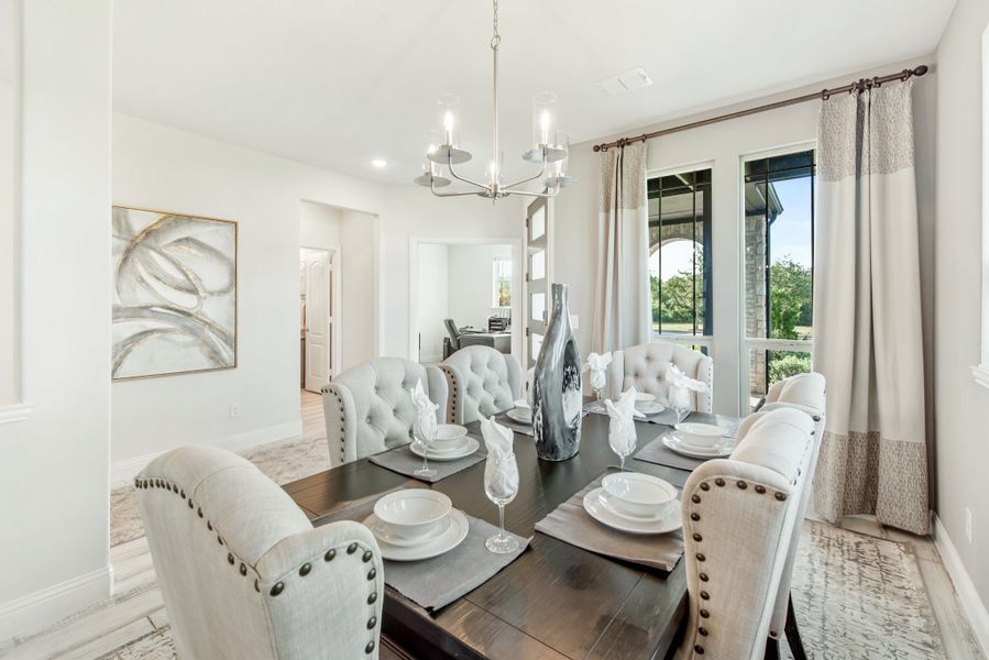 Formal dining room with dark wood table, tufted chairs, chandelier, and large windows with drapes
