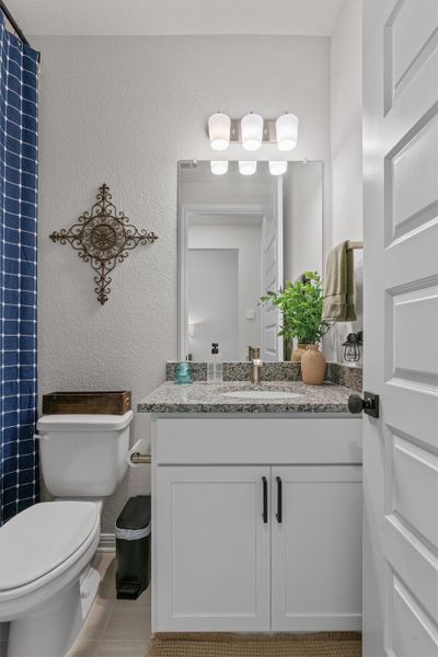 Full bathroom with vanity, a textured wall, and curtained shower