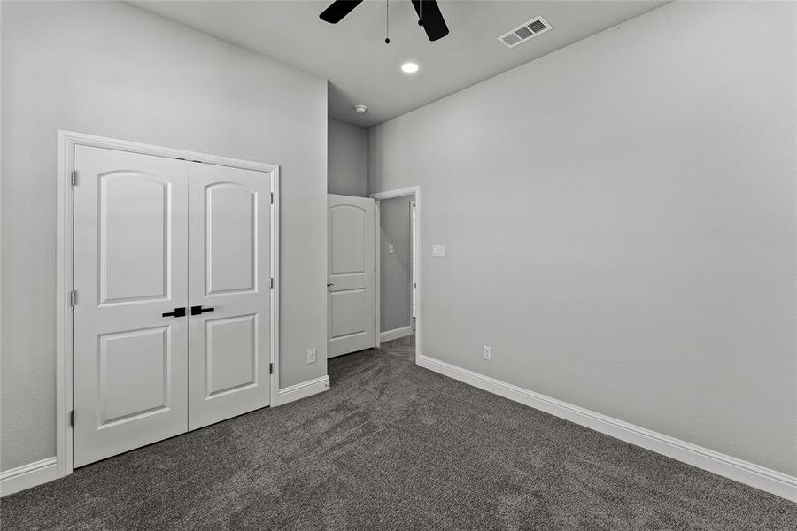 Unfurnished bedroom with dark colored carpet, a closet, and ceiling fan Unfurnished bedroom with dark colored carpet, a closet, and ceiling fan