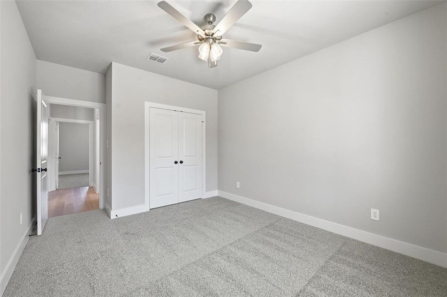 Unfurnished bedroom with carpet, a closet, and ceiling fan Unfurnished bedroom with carpet, a closet, and ceiling fan