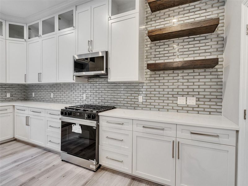Kitchen equipped with gas range, subway tile backsplash and a coffee bar setup
