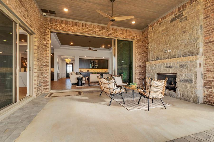 View of patio with an outdoor stone fireplace and a ceiling fan