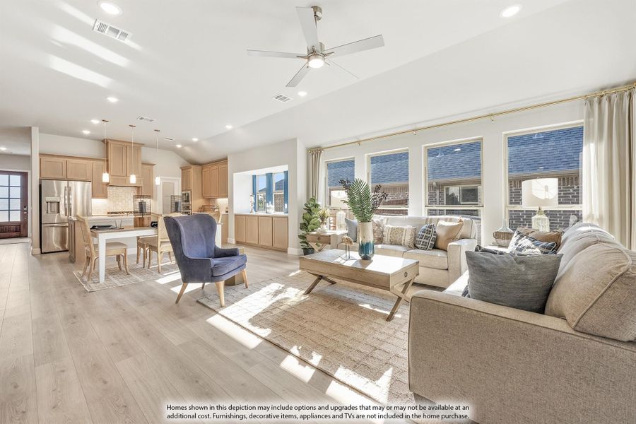 Open-concept living room with ceiling fan and hardwood floors, open to kitchen and dining area with large windows Open-concept living room with ceiling fan and hardwood floors, open to kitchen and dining area with large windows