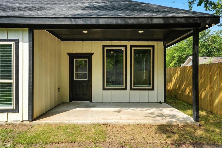 Property entrance featuring roof with shingles and a patio