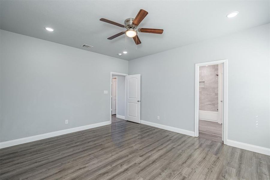 Unfurnished bedroom with baseboards, visible vents, connected bathroom, wood finished floors, and recessed lighting