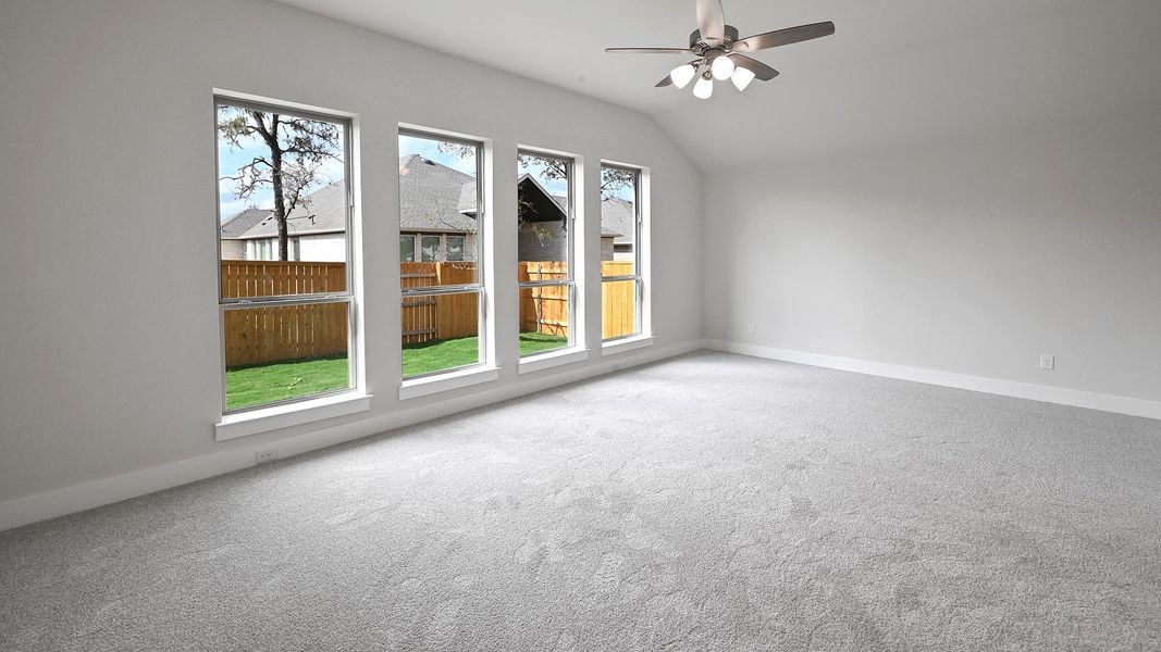 Empty room featuring light colored carpet, lofted ceiling, and ceiling fan Empty room featuring light colored carpet, lofted ceiling, and ceiling fan