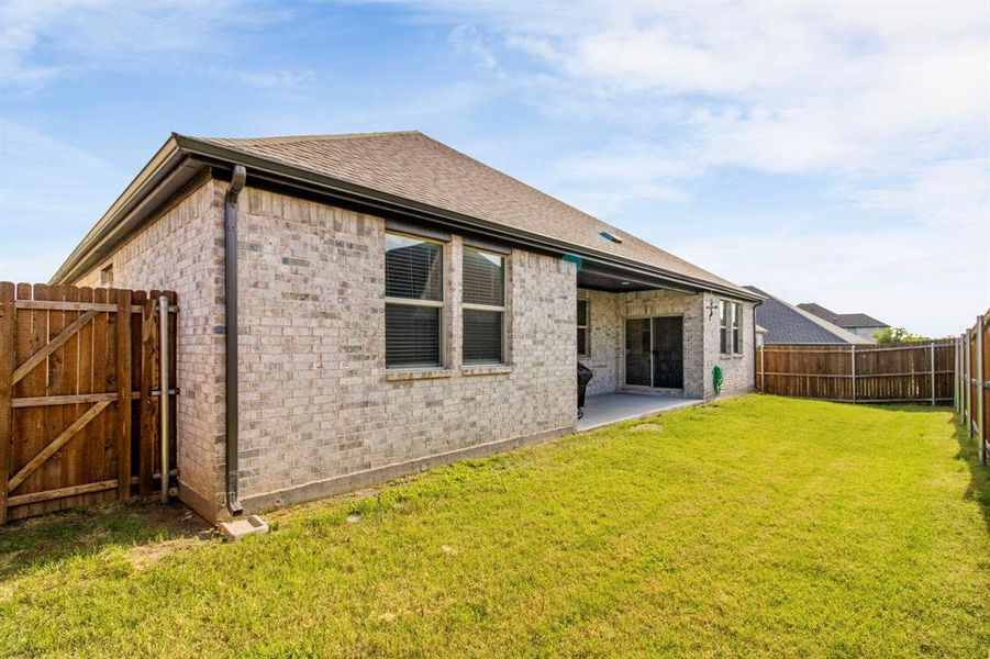 Rear view of property featuring a fenced backyard, brick siding, roof with shingles, a patio, and a gate Rear view of property featuring a fenced backyard, brick siding, roof with shingles, a patio, and a gate