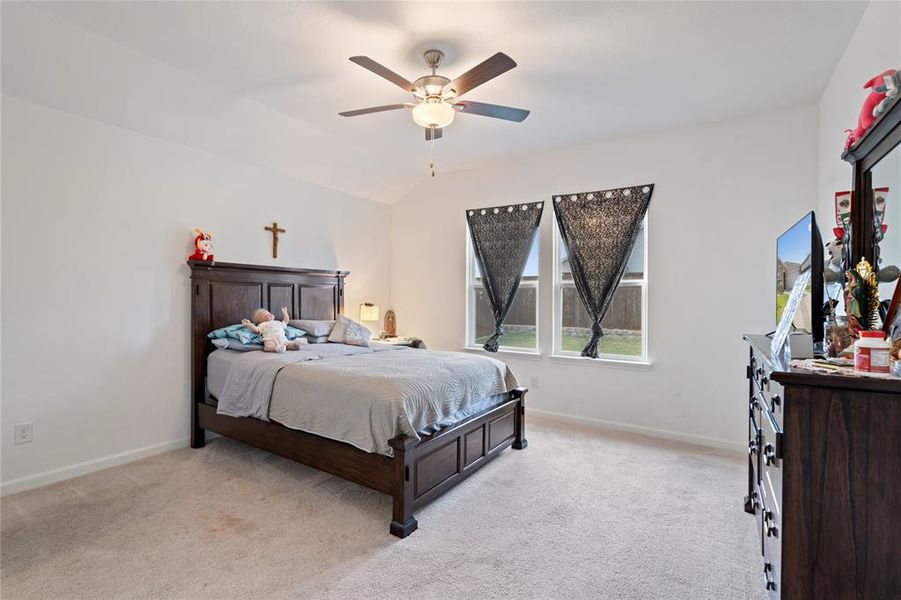 Bedroom with light carpet, a ceiling fan, and vaulted ceiling