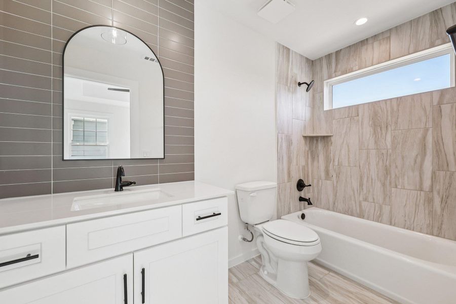 Full bath featuring vanity, washtub / shower combination, and backsplash Full bath featuring vanity, washtub / shower combination, and backsplash