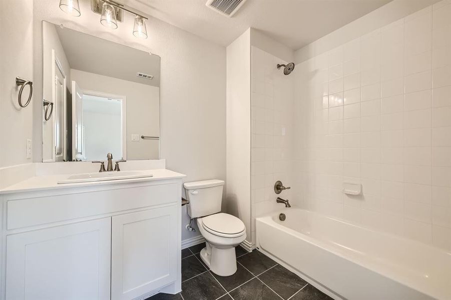 Full bathroom featuring tiled shower / bath, vanity, toilet, and tile patterned flooring