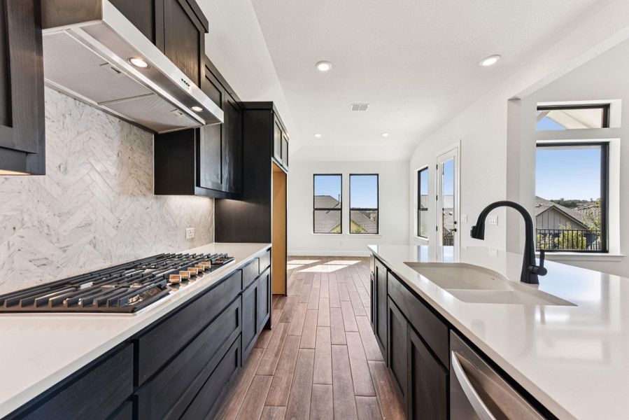 Kitchen with extractor fan, tasteful backsplash, dark wood-style floors, light stone counters, and appliances with stainless steel finishes