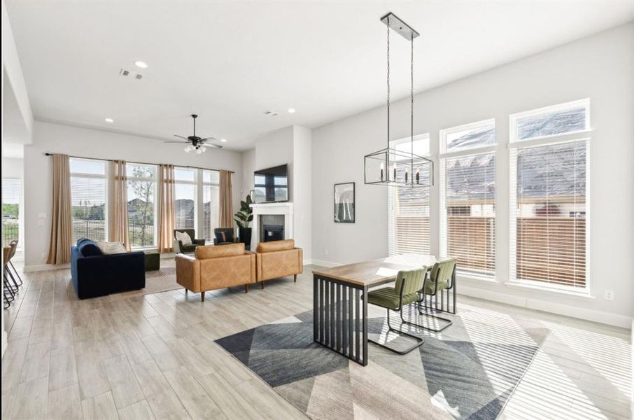 Dining space with a glass covered fireplace, ceiling fan, recessed lighting, light wood finished floors, and a chandelier