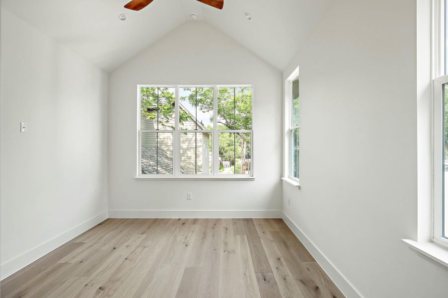 Spare room featuring a ceiling fan, light wood finished floors, lofted ceiling, and baseboards