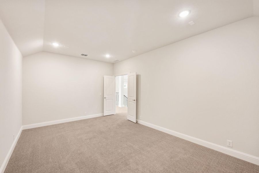 Empty room with beige carpet, white walls, recessed lighting, and open double doors leading to a hallway Empty room with beige carpet, white walls, recessed lighting, and open double doors leading to a hallway