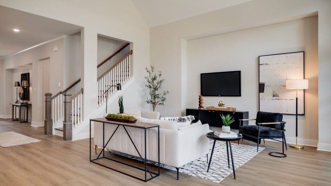 Large living room area with vaulted ceiling next to staircase and kitchen Large living room area with vaulted ceiling next to staircase and kitchen