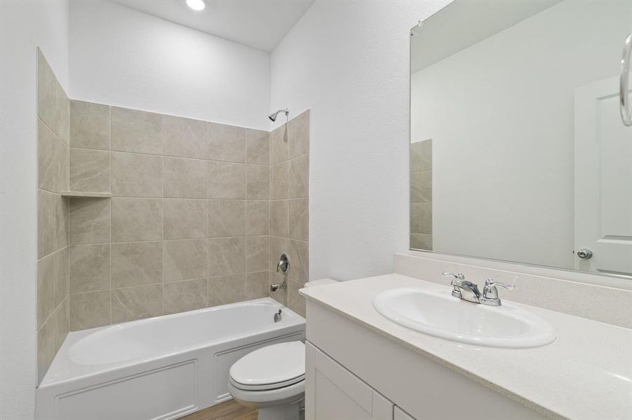 Full bathroom featuring tiled shower / bath combo, vanity, and toilet