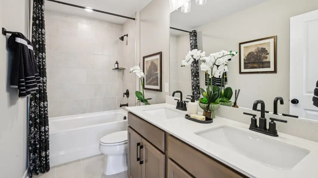 Double sink vanity, toilet, and shower located between secondary bedrooms