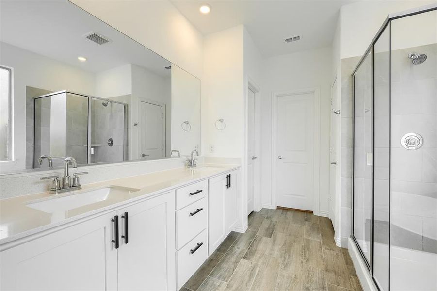 Full bathroom featuring a stall shower, double vanity, light wood-style floors, and recessed lighting Full bathroom featuring a stall shower, double vanity, light wood-style floors, and recessed lighting