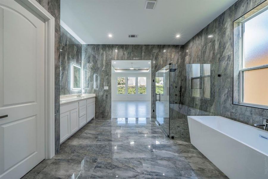 Full bath with tile walls, a freestanding tub, light marble finish flooring, vanity, and a marble finish shower Full bath with tile walls, a freestanding tub, light marble finish flooring, vanity, and a marble finish shower