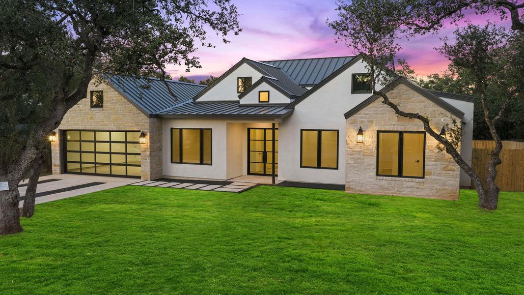 Striking contemporary design blends smooth stucco and light stone under a sleek metal roof.