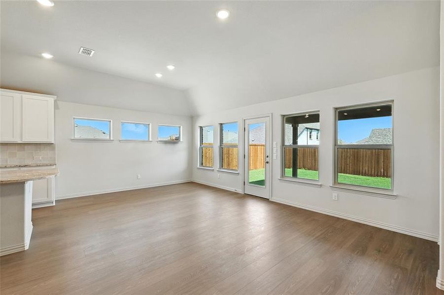 Unfurnished living room featuring recessed lighting, plenty of natural light, vaulted ceiling, and light wood finished floors Unfurnished living room featuring recessed lighting, plenty of natural light, vaulted ceiling, and light wood finished floors