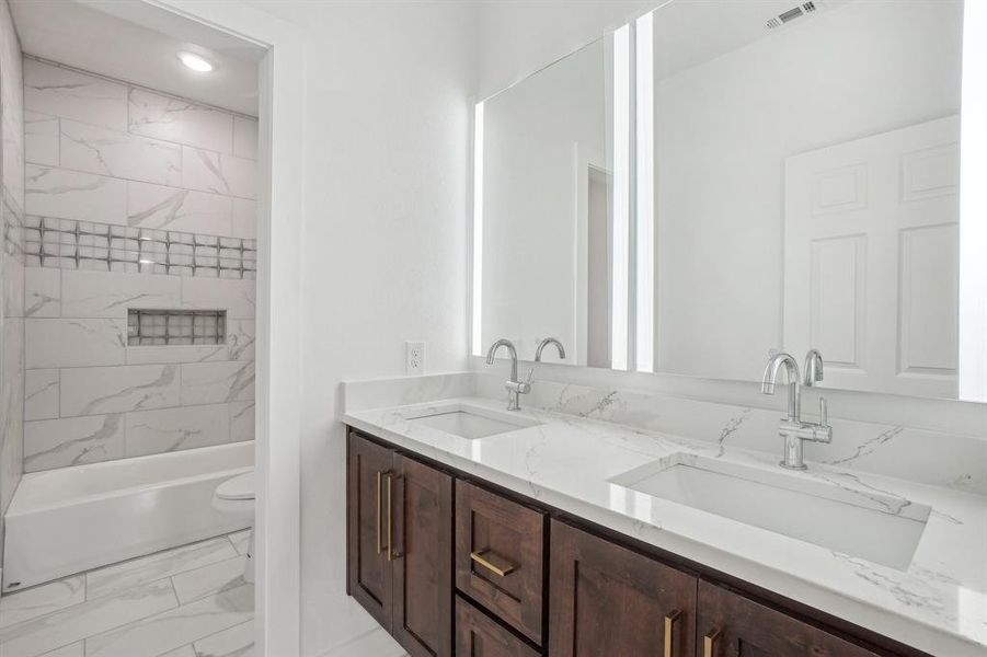 Full bathroom with vanity, tiled shower / bath combo, and toilet