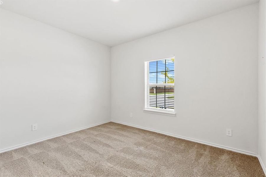 Bright room featuring a window with horizontal blinds and grid pattern, light neutral-toned walls, and plush carpeting