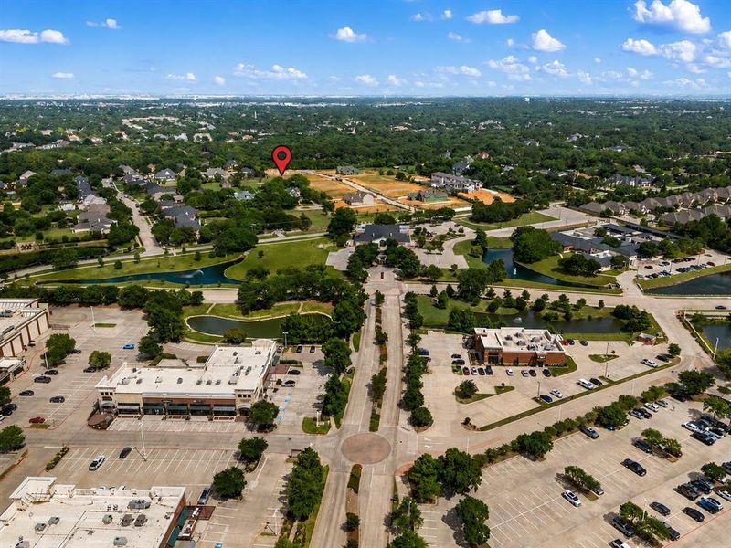 Aerial perspective showcasing a developed suburban landscape featuring residential areas, commercial buildings, and extensive green spaces with water features