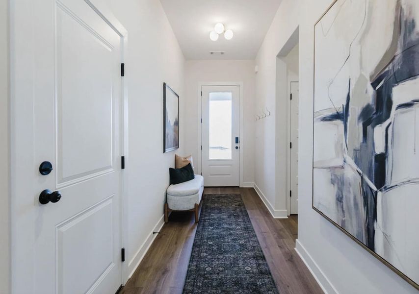 Entryway featuring wood-finish flooring, white trim, and a white front door with clear glass