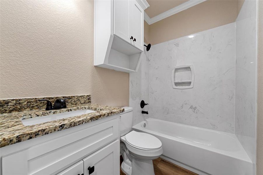 Full bathroom featuring crown molding, shower / tub combination, vanity, wood finished floors, and a textured wall