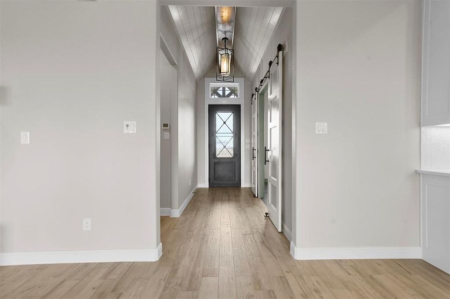 Entryway with a barn door, wooden ceiling, light hardwood / wood-style flooring, and lofted ceiling