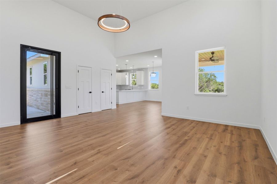 Vaulted ceilings enhance this open-concept living area featuring wood-finish flooring and a modern circular chandelier Vaulted ceilings enhance this open-concept living area featuring wood-finish flooring and a modern circular chandelier