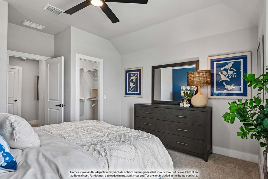 Bedroom with vaulted ceiling, ceiling fan, walk-in closet, and dark wood dresser with mirror Bedroom with vaulted ceiling, ceiling fan, walk-in closet, and dark wood dresser with mirror