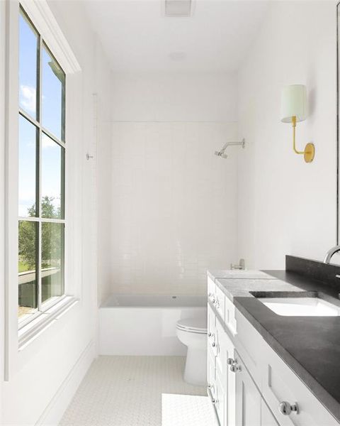 Full bathroom with vanity, toilet, a healthy amount of sunlight, and tiled shower / bath combo