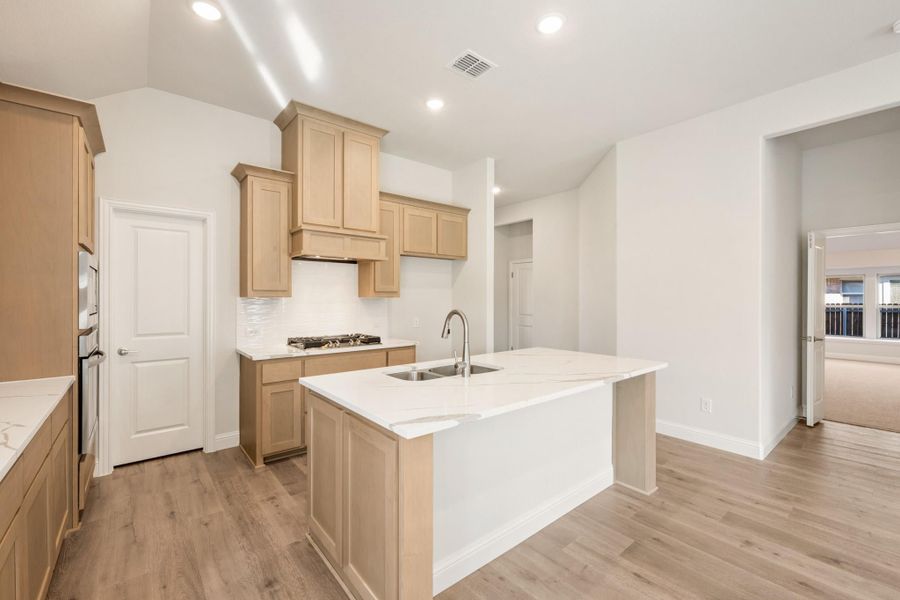 Kitchen with light wood cabinets, white quartz island with sink, and light hardwood floors Kitchen with light wood cabinets, white quartz island with sink, and light hardwood floors