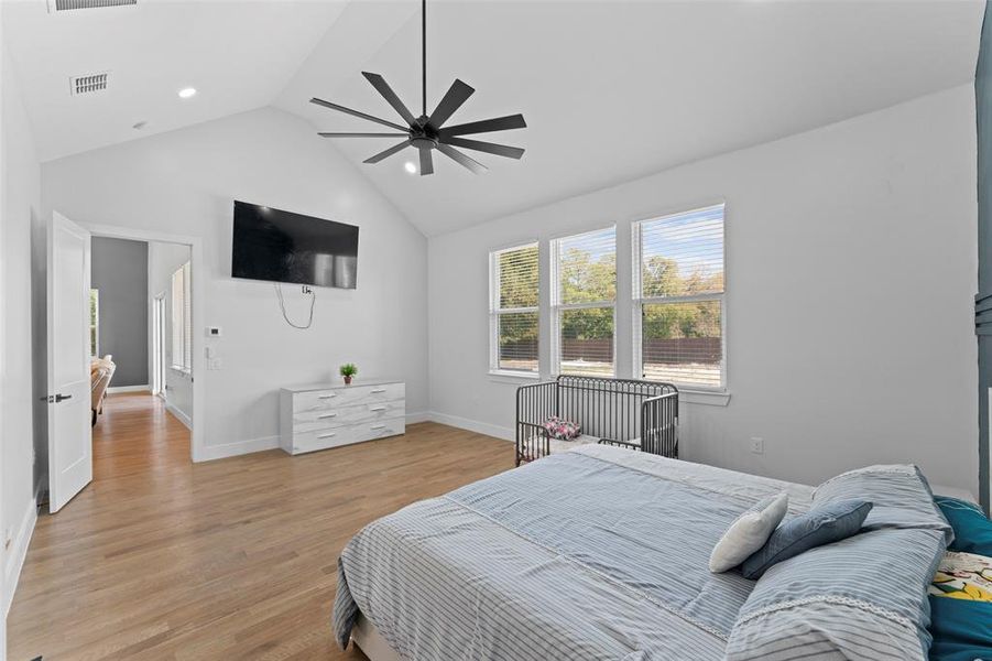 Bedroom featuring light wood-style floors, a ceiling fan, and high vaulted ceiling Bedroom featuring light wood-style floors, a ceiling fan, and high vaulted ceiling