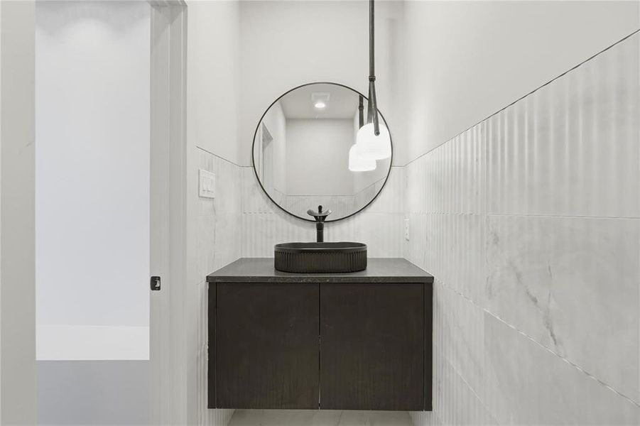 Floating vanity with a dark wood-finish cabinet and a charcoal vessel sink