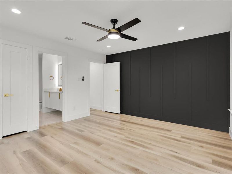 Unfurnished bedroom featuring connected bathroom, ceiling fan, and light hardwood / wood-style flooring