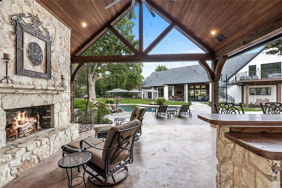 View of patio featuring a bar and an outdoor stone fireplace