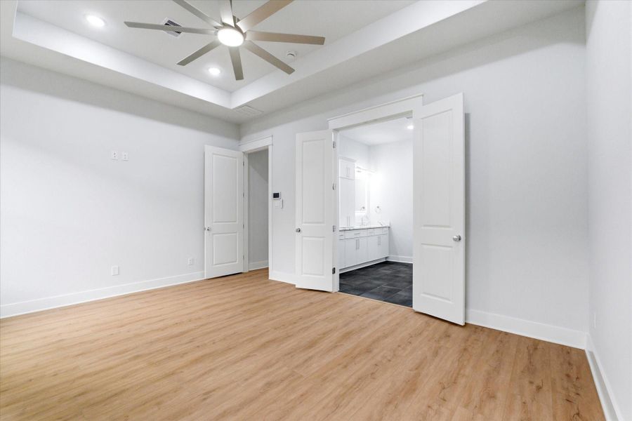 The primary bedroom showcases recessed lighting and 11 foot ceilings, a built in security system control panel and double doors that open directly into your private en-suite.